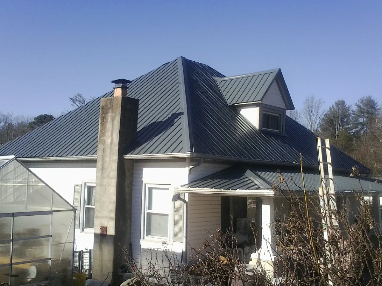 Dark blue standing seam metal roof on a white farmhouse with dormer — Slate & Tile Roof Repair by Roofing Brothers in Fishers