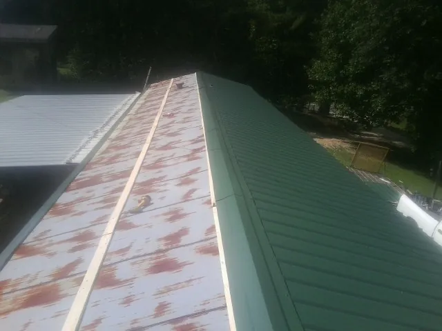 Old rusted panels beside newly installed green metal roofing — Wind Damage Roof Repair by Roofing Brothers in Fishers
