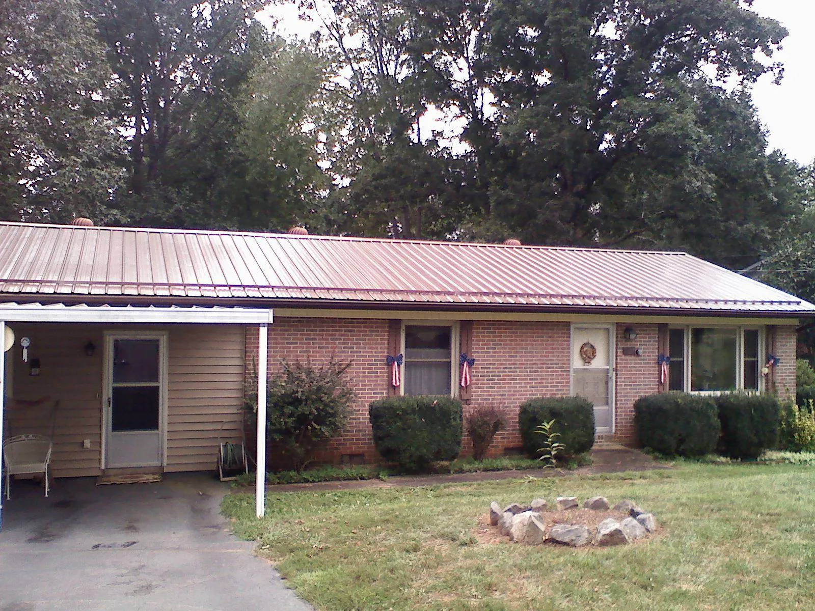 Bronze metal roof and carport on a brick ranch home — Roof Repair work by our crew in Fishers