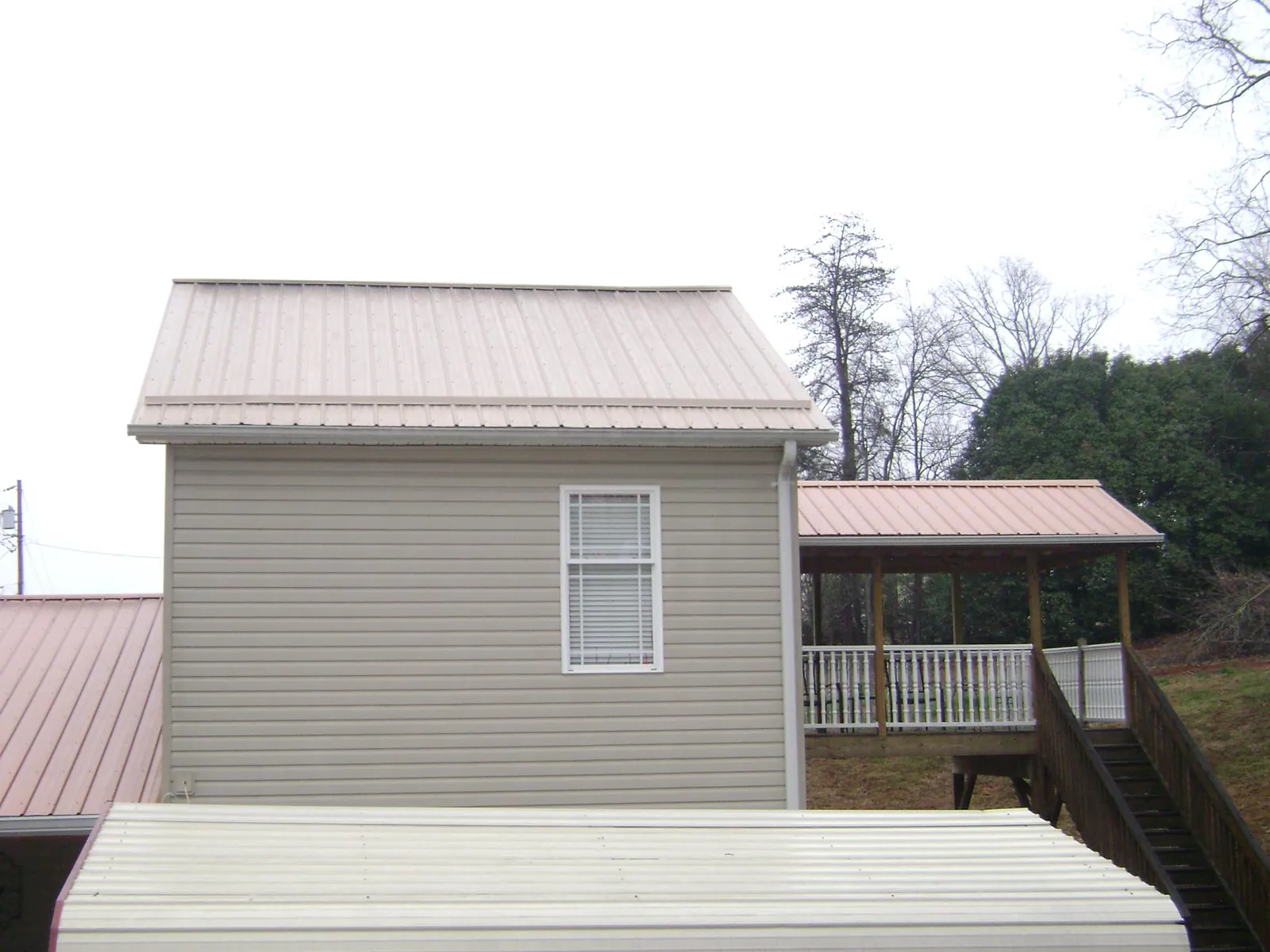 Tan metal roofs on a two story addition and attached porch, from a Roof Replacement job in Fishers